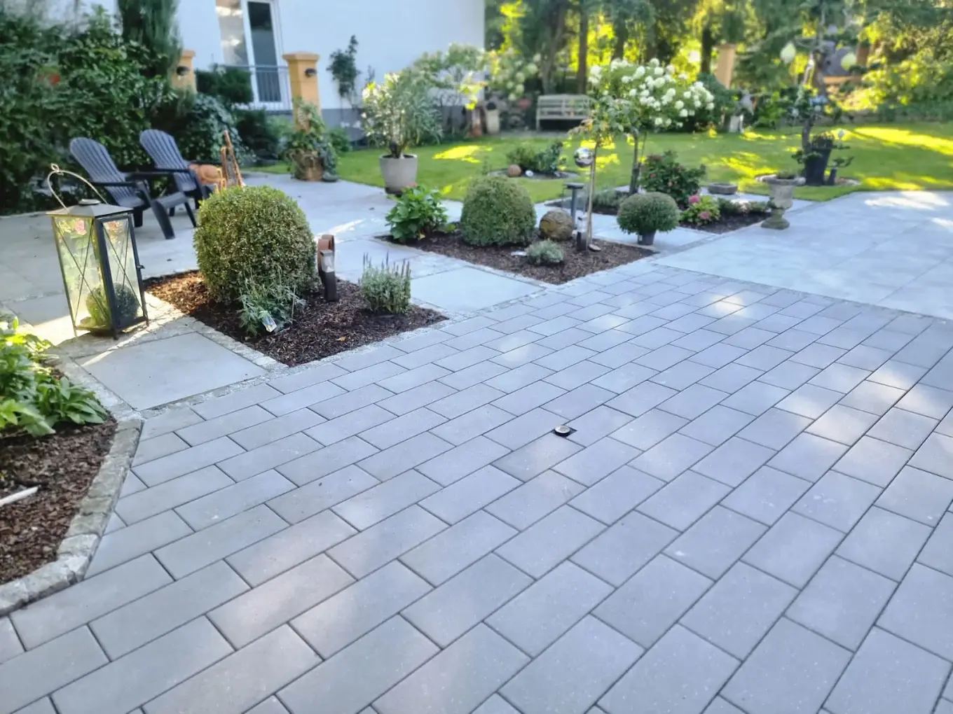 Terrasse mit Bepflanzung und Loungemöbeln im warmen Abendlicht